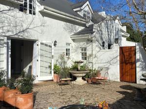 a white house with a courtyard with a fountain at Courtyard on Weder in Greyton