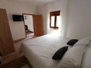 a bedroom with a white bed with two black pillows at Farma & Apartmani OPG Sasa Delic in Korenica +22 photos