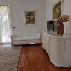 sala de estar con sofá blanco y TV en CasaRò, en Albano SantʼAlessandro