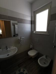 uma casa de banho com um lavatório, um WC e uma janela. em Valle dell'Eden em Grottammare