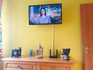 een televisie aan een muur boven een houten dressoir bij Apartament Iulia in Geoagiu Băi