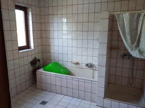 baño con bañera y ducha con un bol verde en Valéria Vendégház, en Balatonföldvár