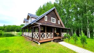ein großes Haus auf einem Rasen mit See in der Unterkunft Sodyba Paštys Poilsinė Su Pirtim in Vozgėliai