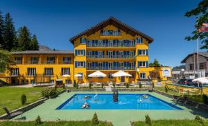 un hôtel avec une piscine en face d'un bâtiment dans l'établissement Grischalodge das Hotel mit Bergblick seit 1929, à Parpan