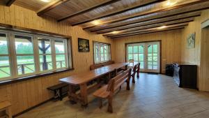 une salle à manger avec une longue table en bois et des bancs dans l'établissement Sodyba Paštys Poilsinė Su Pirtim, à Vozgėliai