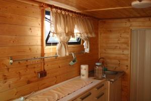 a log cabin kitchen with a sink and a window at V dedine a predsa mimo nej v maringotke na samote in Dechtice