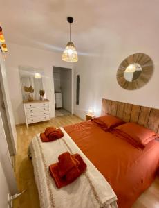 - une chambre dotée d'un lit avec des draps orange et un miroir dans l'établissement Appartement cossy 1 chambre pour 2 pers - rénové - terrasse - parking, à Dinard