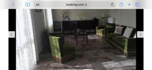 a living room with green couches and a table at KOUMANS RESIDENCE AKOUMIA-TRIOPETRA in Akoumia