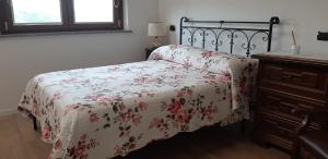 um quarto com uma cama com uma colcha floral e uma cómoda em CASCINA LAI - Oasi Naturalistica - Camere private em Santena