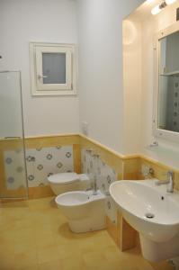 a bathroom with two sinks and a toilet and a mirror at Case Vacanze Margherita in Lipari