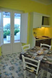 una cocina con mesa y sillas y una cocina con paredes amarillas. en Case Vacanze Margherita, en Lipari
