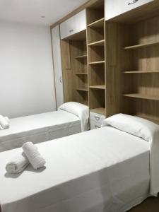 2 Betten in einem Zimmer mit Regalen in der Unterkunft Apartamento vista al puerto de Finisterre II in Fisterra + 7 Fotos