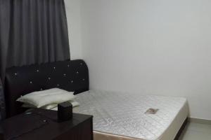 Una cama pequeña con cabecero negro y una mesa. en Equine Park, Seri Kembangan, en Seri Kembangan
