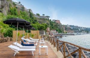 um grupo de cadeiras e guarda-sóis num cais junto à água em Hotel Lorelei Londres em Sorrento