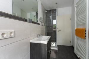 ein weißes Bad mit einem Waschbecken und einer Dusche in der Unterkunft Ferienwohnung am Steinbach 2 in Thale