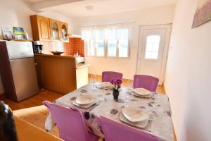 a dining room table with purple chairs and a kitchen at Apartman Krstaš- Gonar in Supetarska Draga