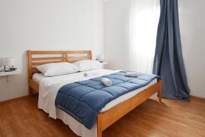 a bed with a blue blanket and two stuffed animals on it at Apartman Krstaš- Gonar in Supetarska Draga