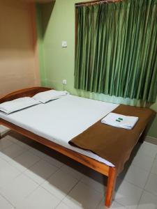 a bed in a room with a green window at Roxel Inn in Port Blair