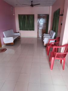 a living room with red chairs and white furniture at Roxel Inn in Port Blair