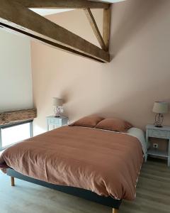 a bedroom with a large bed with two tables and two lamps at Gîte de la Foye - Le Jasmin in Combrand