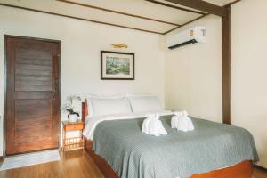 a bedroom with a bed with two towels on it at Villa Mungkala - Colonial Villa in Chiang Rai