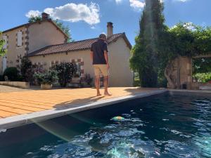 a man standing on the edge of a swimming pool at Chambres d'hôtes de la pilatière in Persac