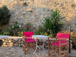 twee stoelen en een tafel en twee tafels en een stenen muur bij Anna s House in Chora in Astypalaia-stad (Chora)