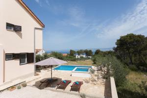a house with a pool and two chairs and an umbrella at Holiday Home Tanja in Sutivan
