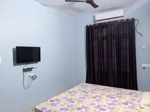 a bedroom with a bed and a television on the wall at Swapnil Homestay in Varanasi
