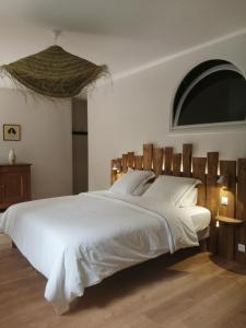 een slaapkamer met een groot wit bed met een houten hoofdeinde bij Chambres d'hôtes de la pilatière in Persac
