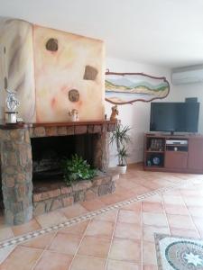 a living room with a stone fireplace and a flat screen tv at Casa vacanze Lilly in Teulada