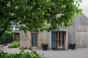 Bed and Breakfast Bedstay op 8 في Dalen: منزل خشبي بأبواب زجاجية وشجرة