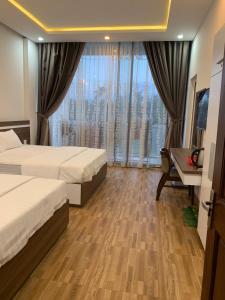 a hotel room with two beds and a desk and a window at Minh Hoàng Hotel in Tuy Hoa