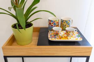 a table with three cups and a potted plant on it at Baia Flegrea Meublè in Bacoli