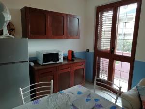 Una pequeña cocina con una mesa y un microondas. en Prendas Antigas - vacanze a Teulada, en Teulada 24 fotos más