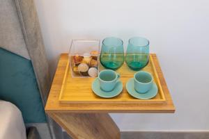 a table with three glasses and a tray with cups and plates at Baia Flegrea Meublè in Bacoli