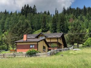 a house in a field next to a fence at Cabana Todireni Vatra Dornei in Vatra Dornei