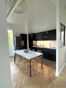 a dining room with a table and chairs and a kitchen at Piscine et jacuzzi Loft ravissant dans une maison basque in Anglet