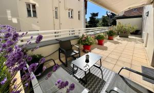 een balkon met tafels en stoelen en paarse bloemen bij 120m2 avec deux terrasses ensoleillées à Biarritz in Biarritz