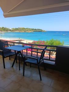 einen Tisch und Stühle auf einem Balkon mit Blick auf den Strand in der Unterkunft Buganvilla Sea View apts in Agia Pelagia