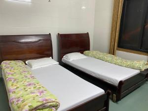 two twin beds in a room with a window at Khách sạn AMI in Vinh