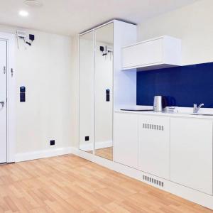 a kitchen with white cabinets and a wooden floor at Blue Side Orbi City in Batumi