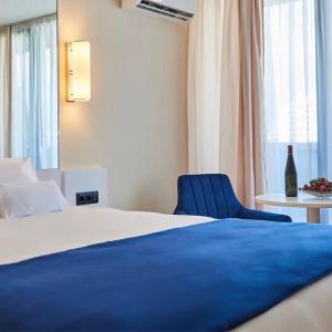 a hotel room with a bed and a blue chair at Blue Side Orbi City in Batumi