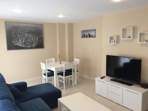 een woonkamer met een blauwe bank en een tv bij Tarifa Apartamento piscina ideal familia niños in Tarifa