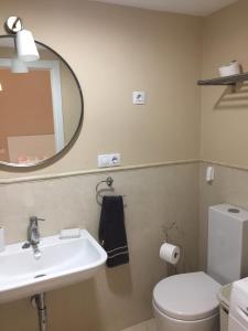 a bathroom with a sink and a toilet and a mirror at Tarifa Apartamento piscina ideal familia niños in Tarifa