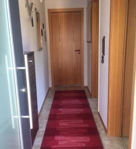 a hallway with a red rug and a wooden door at Ferienwohnung Plettenbergblick in Dotternhausen