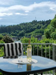 una bottiglia di vino seduta su un tavolo con un bicchiere di Cantinho do Rio a Ponte da Barca