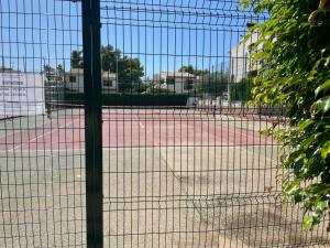 um campo de ténis visto através de uma cerca de arame em Adosado con piscina y tenis em Benicàssim