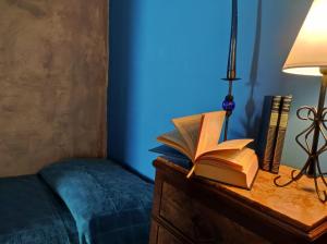 an open book on a dresser with a lamp and a bed at Le DueLamie in Sessa Cilento