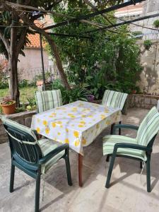 a table with two chairs and a table with a tablecloth with yellow flowers at Rooms Ljubo in Dubrovnik